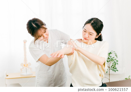 A patient who came to a manipulative clinic / osteopathic clinic to treat arm pain and a woman who is a manipulative therapist / masseuse / therapist / doctor 100621557