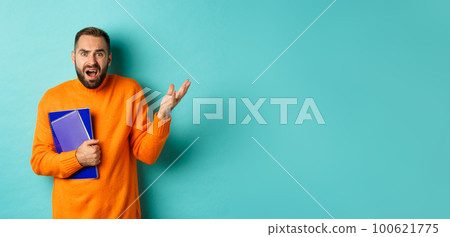 Education. Confused and disappointed man arguing, holding notebooks and complaining, standing over light blue background Education. Confused and disappointed man arguing, holding notebooks and complaining, standing over light blue background 100621775