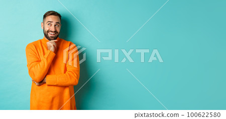 Thoughtful bearded guy making choice, shopping and looking at upper left corner, smiling satisfied, standing over turquoise background Thoughtful bearded guy making choice, shopping and looking at upper left corner, smiling satisfied, standing over turquoise background 100622580