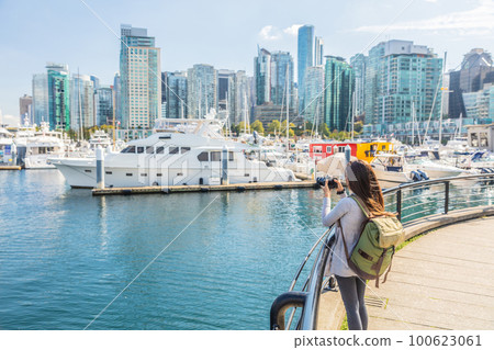 Vancouver Canada tourist woman taking picture with camera at Coal Harbour on summer holidays in canadian city. Urban lifestyle. 100623061