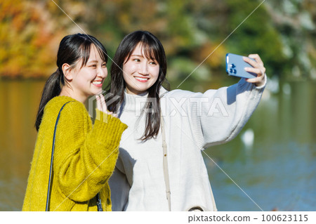 年輕女子在公園的水邊自拍 100623115