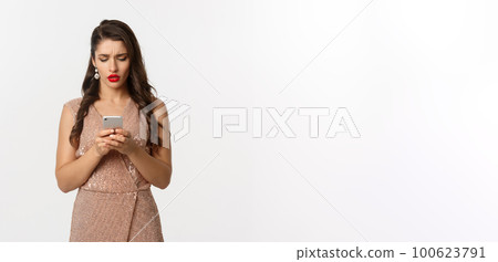 Christmas party and celebration concept. Woman reading message with sad and confused face, wearing elegant dress, standing over white background Christmas party and celebration concept. Woman reading message with sad and confused face, wearing elegant dress, standing over white background 100623791