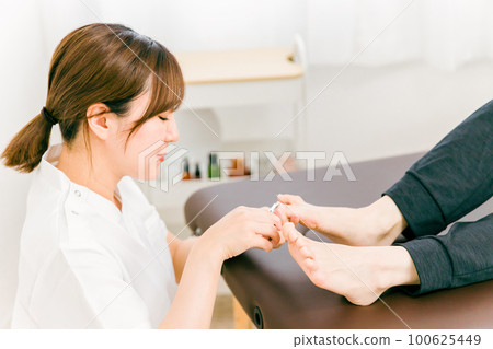 一位到骨科/脊椎按摩診所治療腿部受傷的患者和一位脊椎按摩師/按摩師/治療師/醫生的女士 100625449