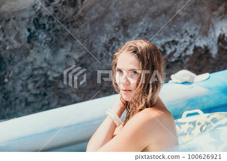 Woman summer sea. Happy woman swimming with inflatable donut on the beach in summer sunny day, surrounded by volcanic mountains. Summer vacation concept. Woman summer sea. Happy woman swimming with inflatable donut on the beach in summer sunny day, surrounded by volcanic mountains. Summer vacation concept. 100626921