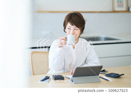 A woman taking a break with a mug while working from home A woman taking a break with a mug while working from home 100627825