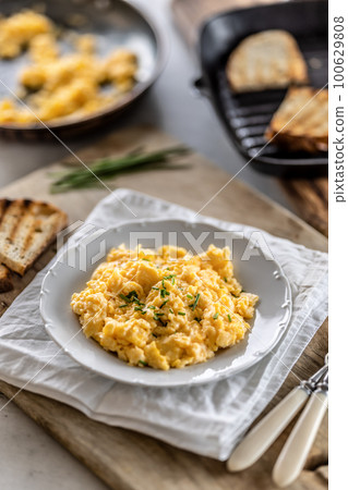Silky-smooth scrambled eggs made to perfection and served in a plate for breakfast Silky-smooth scrambled eggs made to perfection and served in a plate for breakfast 100629808