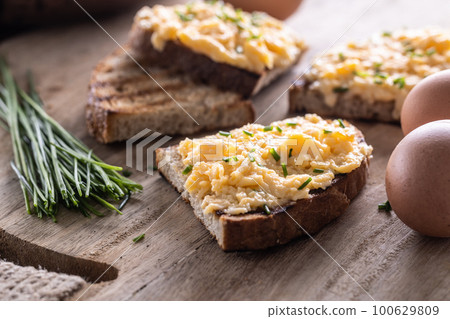 Fresh scrambled eggs spread on a slice of bread with whole eggs and fresh chive on the side Fresh scrambled eggs spread on a slice of bread with whole eggs and fresh chive on the side 100629809