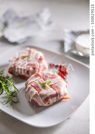 Cheese wraps preparation by wrapping them in a bacon slices griddle before baking 100629818