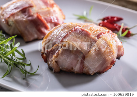 Crispy bacon wraps served on a plate with rosemary and chillies 100629819