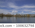 Pond with overhanging clouds against a blue sky 100632798