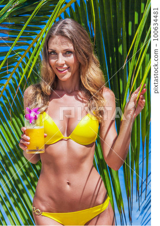 Woman with cocktail on beach 100634481