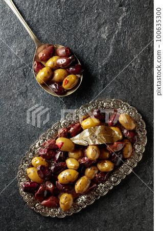 Spicy olives on a black stone table. Spicy olives on a black stone table. 100635300