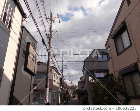 在陰雲密佈的天空下,日本的居民區和街道兩旁林立的電線桿和電線構成了一幅美麗的景象。 在陰雲密佈的天空下,日本的居民區和街道兩旁林立的電線桿和電線構成了一幅美麗的景象。 100638225