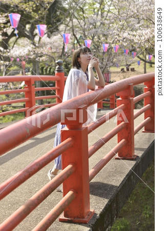 擺在櫻花公園的一位年輕、苗條的微笑婦女 100638649