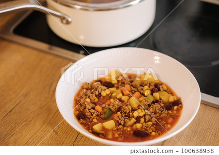 Finished traditional Mexican dish in a plate near the saucepan. Spicy food 100638938