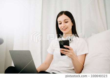 Beautiful woman has woken up on a white bed and holding coffee in the morning at home in morning Beautiful woman has woken up on a white bed and holding coffee in the morning at home in morning 100640323