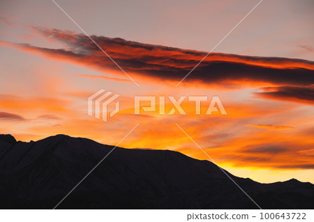silhouette of the mountain and the sunset sky. Colorful red sunset, in the foreground the silhouette of the ridge of the rocky mountains 100643722