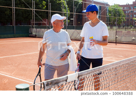 grandfather and grandson talking on court playing tennis grandfather and grandson talking on court playing tennis 100648388