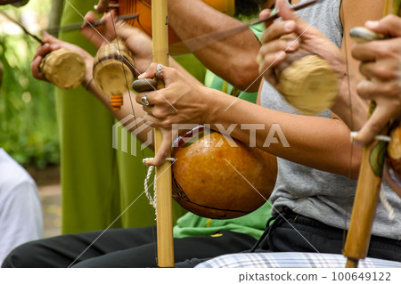 Several musicians playing an Afro Brazilian percussion musical instrument 100649122