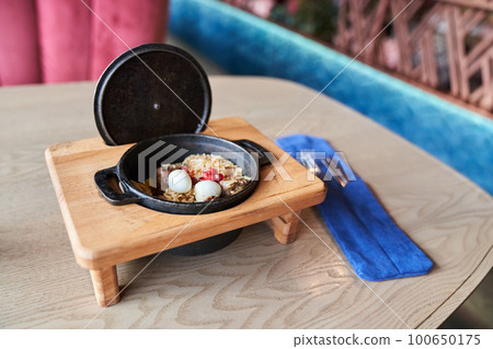 Pilaf on a platter with beef on a wooden background with appliances. The concept of Oriental cuisine. Homemade Uzbek beef pilaf is served in cast-iron dishes. Space for copying. High quality photo 100650175