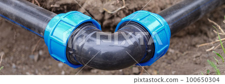 Elbow fitting, pvc pipes at bend in dirt trench outdoors 100650304