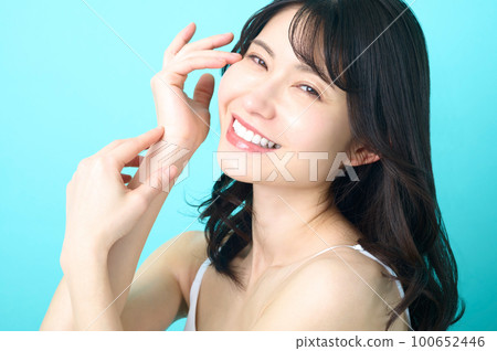 Beauty image of a sleeveless woman posing in front of a blue background Beauty image of a sleeveless woman posing in front of a blue background 100652446