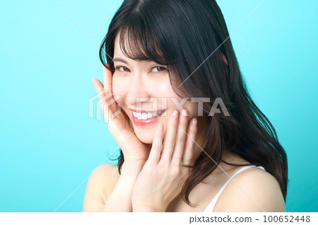 在藍色背景前擺姿勢的無袖女人的美女形象 在藍色背景前擺姿勢的無袖女人的美女形象 100652448