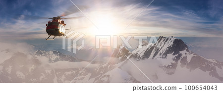 Helicopter flying over the Rocky Mountains during a colorful sunset. 100654043