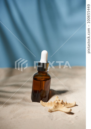 Summer sunscreen essence on sand background with seashells and starfish. Summer sunscreen essence on sand background with seashells and starfish. 100655449