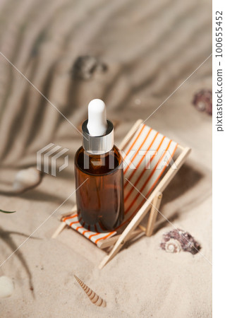 Summer sunscreen essence in deck chair on the sand backgroundwith shells ans seastar. B 100655452