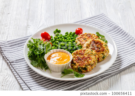 crab cakes with sauce, green peas, tomatoes crab cakes with sauce, green peas, tomatoes 100656411