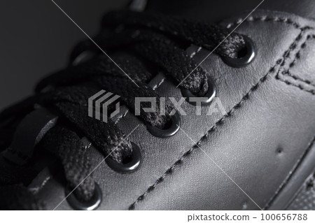 Part of a black boot with laces. A fragment of dark shoes. A piece of sneaker. 100656788