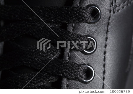 Part of a black boot with laces. A fragment of dark shoes. A piece of sneaker. 100656789