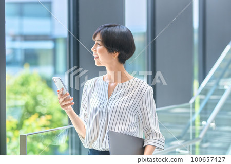Middle business woman operating a smartphone in the office Photography cooperation: LINK FOREST Middle business woman operating a smartphone in the office Photography cooperation: LINK FOREST 100657427