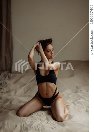 Attractive model posing in studio with sea sand. 100657465