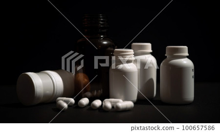 Pill bottles with spilling medicine tablets on dark background 100657586
