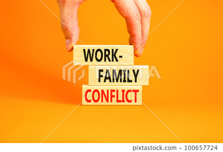 Work-family conflict symbol. Concept words Work-family conflict on wooden block on a beautiful orange table orange background. Businessman hand. Business work-family conflict concept. Copy space. Work-family conflict symbol. Concept words Work-family conflict on wooden block on a beautiful orange table orange background. Businessman hand. Business work-family conflict concept. Copy space. 100657724