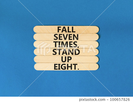 Stand up symbol. Concept words Fall seven times stand up eight on wooden stick. Beautiful blue table blue background. Business stand up concept. Copy space. 100657826