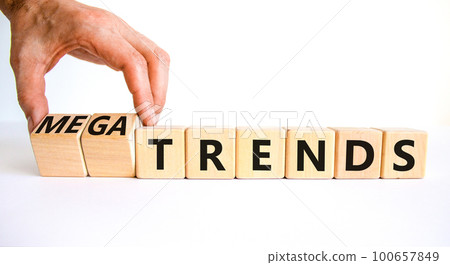 Trends or megatrends symbol. Businessman turns cubes and changes words trends to megatrends. Beautiful white table, white background, copy space. Business and trends or megatrends concept. 100657849