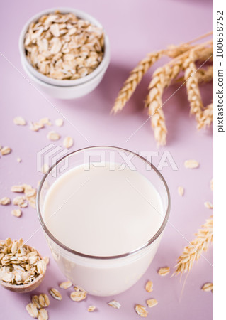 A glass of fresh oat milk and oatmeal. Vegan dairy-free organic drink. Vertical view A glass of fresh oat milk and oatmeal. Vegan dairy-free organic drink. Vertical view 100658752