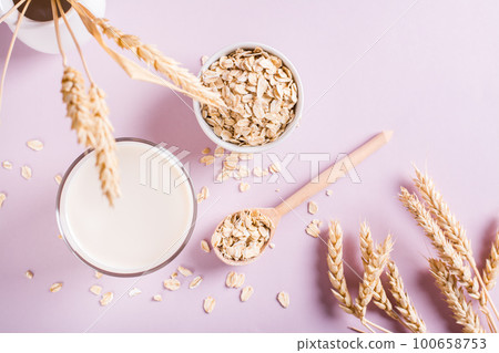 Homemade oat milk in a glass and oatmeal on the table. Alternative to lactose. Top view Homemade oat milk in a glass and oatmeal on the table. Alternative to lactose. Top view 100658753