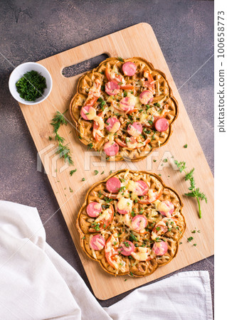 Appetizing pizza waffle with vegetables, sausages and cheese on a board. Top and vertical view Appetizing pizza waffle with vegetables, sausages and cheese on a board. Top and vertical view 100658773