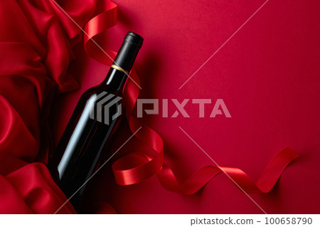 Bottle of red wine on a red background. 100658790