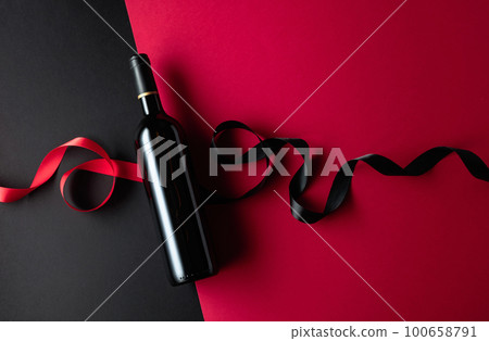 Bottle of red wine with satin ribbons. 100658791