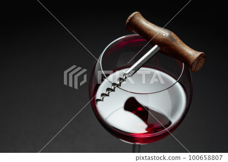 Glass of red wine and corkscrew. Glass of red wine and corkscrew. 100658807