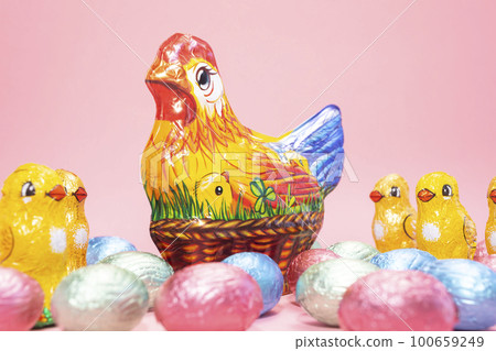 Closeup Chocolate hen, little chickens with colorful bright sweet eggs wrapped in foil on festive Easter pink background. Confectionery, sweet-shop,candied children treat concept. Copyspace,horizontal Closeup Chocolate hen, little chickens with colorful bright sweet eggs wrapped in foil on festive Easter pink background. Confectionery, sweet-shop,candied children treat concept. Copyspace,horizontal 100659249