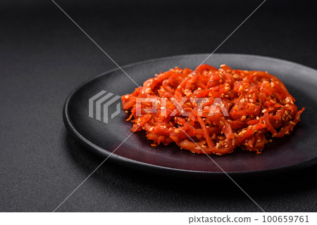 Dried squid chopped into slices and seasoned with sesame seeds and spices 100659761