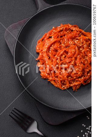 Dried squid chopped into slices and seasoned with sesame seeds and spices 100659767