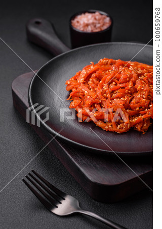 Dried squid chopped into slices and seasoned with sesame seeds and spices Dried squid chopped into slices and seasoned with sesame seeds and spices 100659768
