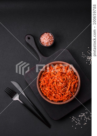 Dried squid chopped into slices and seasoned with sesame seeds and spices 100659788